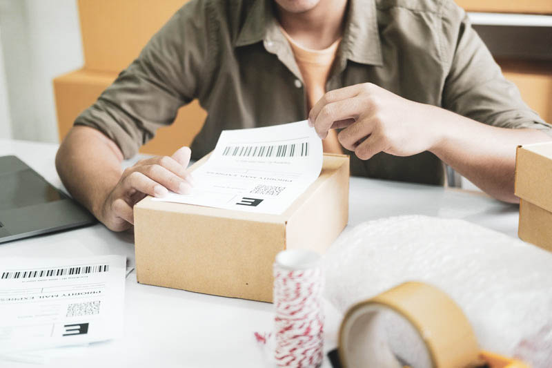 Young entrepreneur packing online order product for shipping.